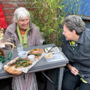 two members of MUCH laughing sitting outside a restaurant